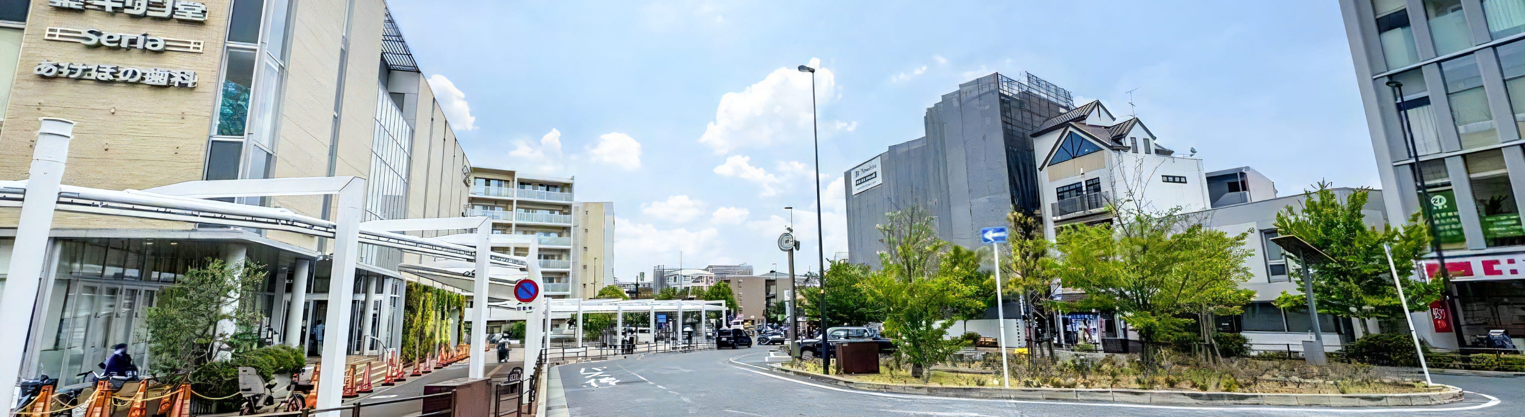 スーパー「阪急オアシス」などが入る商業施設「Bivi」前のロータリーの風景。道路は円形に整備され、周囲には緑が配置されている。青空の下、近代的な建物と住宅が調和した風景。