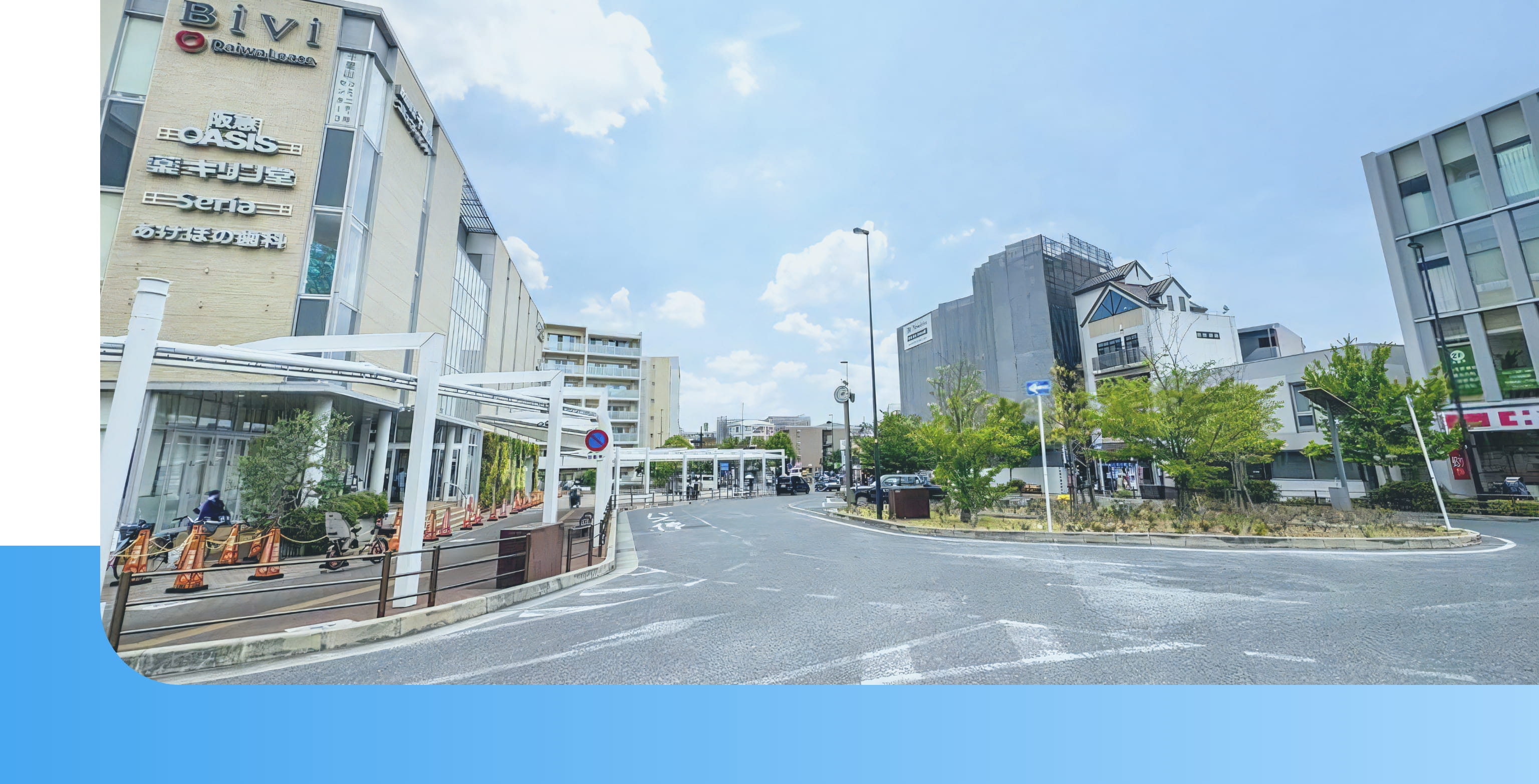 スーパー「阪急オアシス」などが入る商業施設「Bivi」前のロータリーの風景。道路は円形に整備され、周囲には緑が配置されている。青空の下、近代的な建物と住宅が調和した風景。